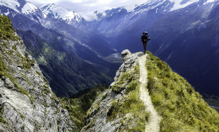 traveler at the edge of a cliff with amazing view behind him