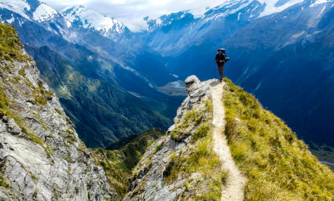 traveler at the edge of a cliff with amazing view behind him